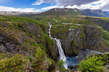 Stunning view of Voringsfossen waterfall cascading into a gorge surrounded by greenery and mountains