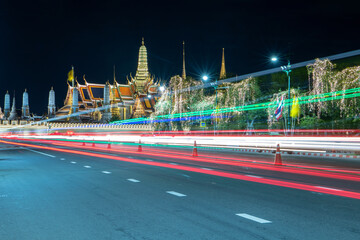 Obraz premium Long exposure light trails in front of the Grand Palace and Wat Phra Kaeo at night , Bangkok, Thailand