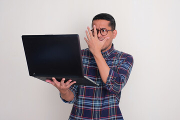 A man showing scared expression when looking at his laptop