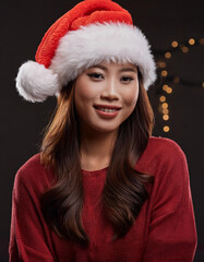Portrait of beauty Asian woman wearing Santa-Claus hat with happy expression for Christmas celebration on dark background