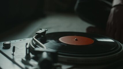 Close-up view of unknown young man putting on vinyl record and turning on player in dim light