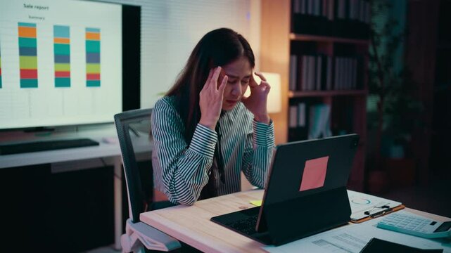 Exhaustion fills the office as a businesswoman struggles with a severe headache while working late on her laptop. Stress and pressure mount during the night, leading to frustration and burnout