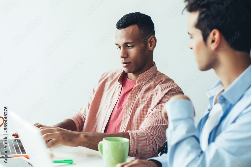 Poster skilled male programmers in casual wear cooperating on design for new application on laptop device c