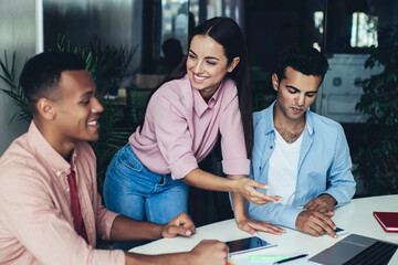 Skilled male and female coworkers enjoying time for communication and collaboration on information for project, positive group of multiracial colleagues browsing internet on modern laptop computer