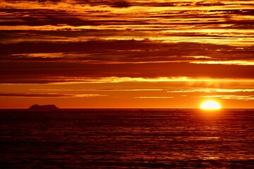 Stunning ocean sunset with a ship silhouette on the horizon and vibrant orange sky.