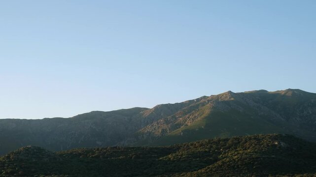 View panning across the evening sun on the mountains of the Balagne region of Corsica, Monte Parteo, Monte Tolu and Monte Grosso and the village of Speloncato