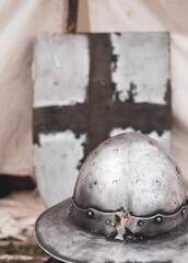 Close-up of a medieval helmet and shield with a cross, showcasing historical armor and weaponry