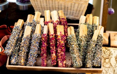 Herbal smudge sticks displayed in a wooden tray.