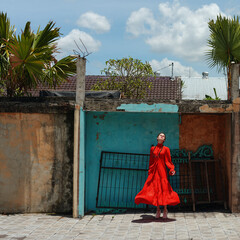 Vibrant woman in red dress posing in front of colorful modern architecture