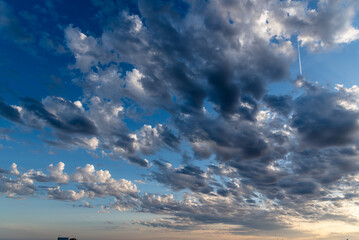 Beautiful white puffy clouds against blue sky during dramatic sunset