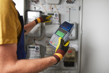 Technician reading consumption and charging on a wireless electricity power meter station in a building.	
