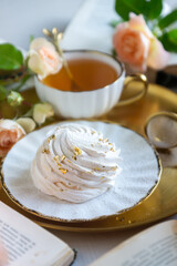 On the white table there is hot tea, cakes and delicate roses.