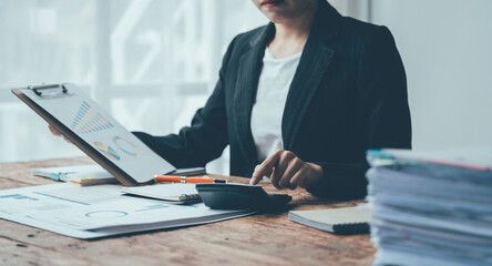 Financial Focus: A businesswoman in a sharp black suit meticulously analyzes charts and crunches...