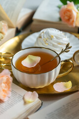 On the white table there is hot tea, cakes and delicate roses.