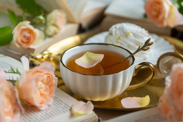 On the white table there is hot tea, cakes and delicate roses.