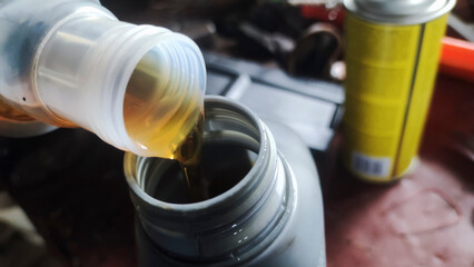 Pouring motor oil from a container into a bottle, concept of oil change.