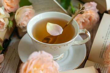 On the white table there is hot tea, cakes and delicate roses.
