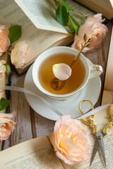 On the white table there is hot tea, cakes and delicate roses.