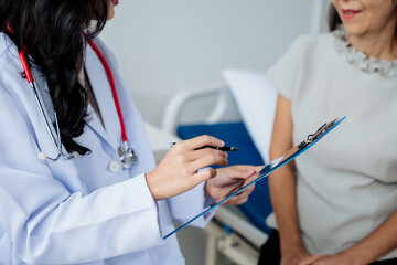 The doctor takes interview the old lady in retired life patient's history and symptoms and explain discuss treatment method to patient in hospital nursing home aged care by using insurance planning