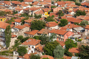 Densely packed, colorful houses with terracotta roofs and scattered trees in a bustling urban...