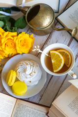On the white table there is hot tea, cakes and delicate roses.