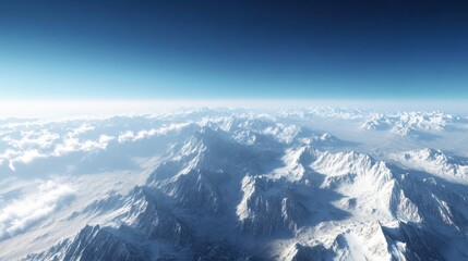 Fototapeta premium A high-altitude view of a mountain range with snow-covered peaks and a clear, bright sky, with distant clouds on the horizon.