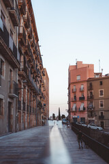A stunning urban street featuring intricate historic architecture illuminated by the soft glow of evening light in Tarragona, Spain