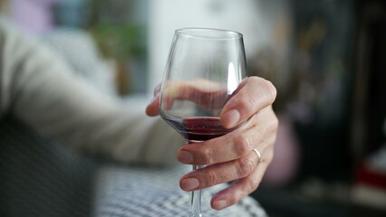 Close-up of an elderly man's hand holding a glass of red wine