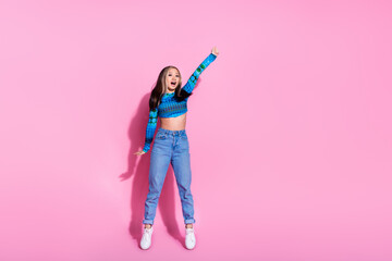 Full length photo of adorable lovely girl wear print top jumping high tacjing arm empty space isolated pink color background