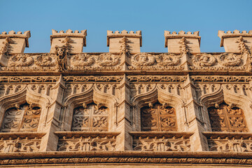 Explore the stunning carvings and detailed architecture of this historic facade under the clear blue sky in Valencia, Spain