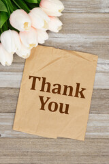 Thank you note with light pink tulips bouquet on butcher paper on wood