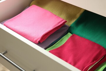 Chest of drawers with different folded clothes, closeup