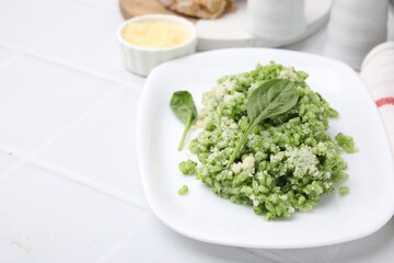 Delicious spinach risotto with parmesan cheese on white tiled table