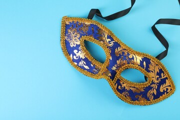 One beautiful carnival mask on light blue background, top view. Space for text