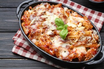 Delicious al forno pasta in baking dish on wooden table, closeup