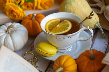 Cup of tea with orange and small pumpkins on white table, September.