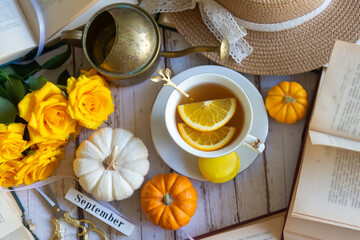 Cup of tea with orange and small pumpkins on white table, September.