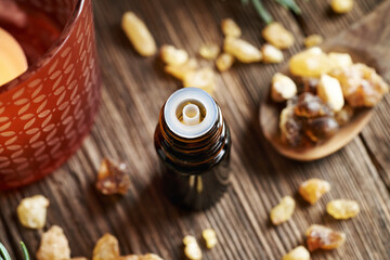 A dropper bottle of frankincense essential oil with boswellia resin on a wooden table