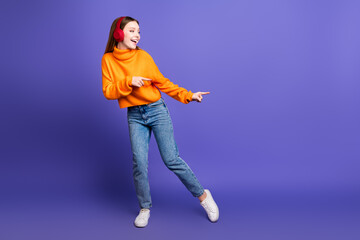 Photo portrait of blonde hair cheerful teenager girl in orange turtleneck and jeans boogie woogie dance isolated on purple color background