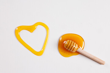 honey spoon with spilled honey in the shape of a heart on a white background top view