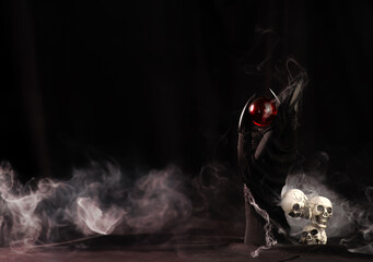 Witch Hands and magic crystal sphere with smoke and skull on black background
