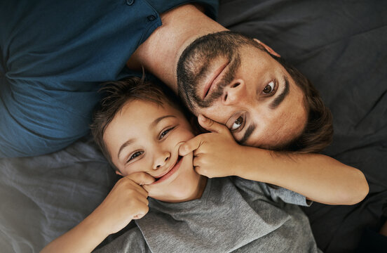 Funny, portrait and child with father on bed for bonding, connection or family time together. Silly, goofy and top view of boy kid with dad for joke, comic or comedy face for humor in bedroom at home