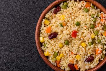 Boiled wheat bulgur porridge with vegetables peppers, peas, corn