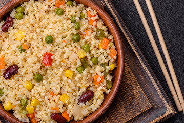 Boiled wheat bulgur porridge with vegetables peppers, peas, corn