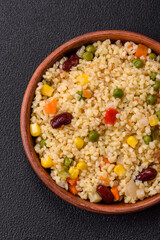 Boiled wheat bulgur porridge with vegetables peppers, peas, corn