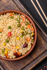 Boiled wheat bulgur porridge with vegetables peppers, peas, corn