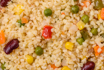 Boiled wheat bulgur porridge with vegetables peppers, peas, corn
