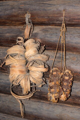 Woven bast shoes hang on the wall. Pairs of woven shoes