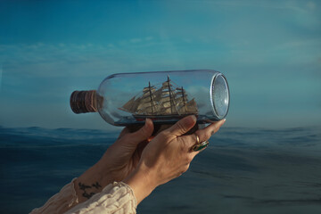 Hands holding a ship in a bottle