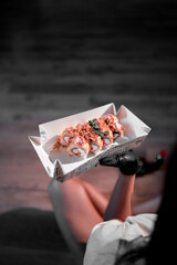 A young woman eats sushi with chopsticks while sitting on the floor in the lotus position. Concept of sushi and rolls